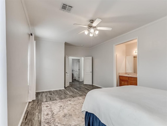 bedroom featuring baseboards, ensuite bath, visible vents, crown molding, and wood finished floors
