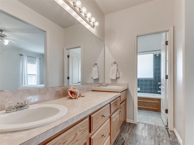 bathroom with a sink, double vanity, a bath, and wood finished floors