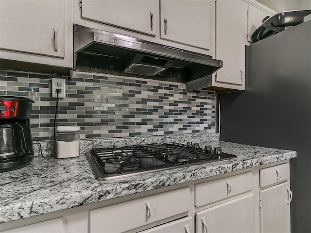 5416 S Independence Ave, Oklahoma City, OK 73119 - kitchen featuring tasteful backsplash, stainless steel gas cooktop, light countertops, white cabinets, and under cabinet range hood