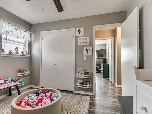 5416 S Independence Ave, Oklahoma City, OK 73119 - recreation room with a textured ceiling, baseboards, a ceiling fan, and wood finished floors