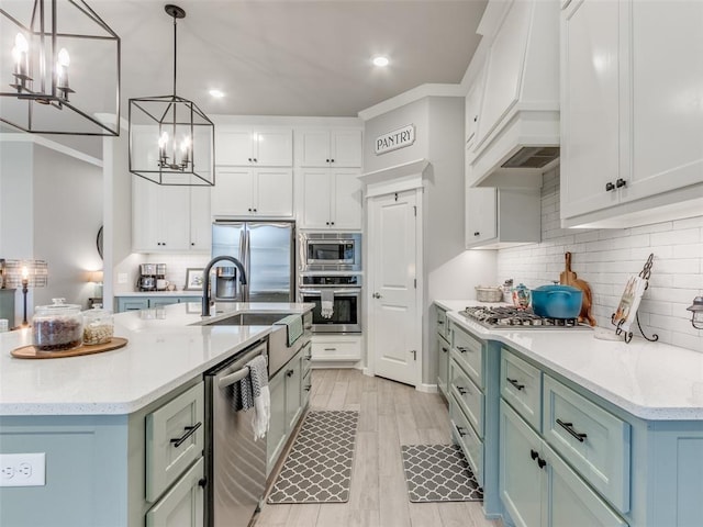 kitchen featuring stainless steel appliances, custom range hood, a chandelier, a sink, and backsplash