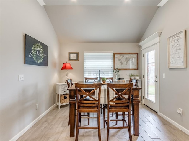 dining room featuring lofted ceiling, plenty of natural light, light wood-type flooring, and baseboards