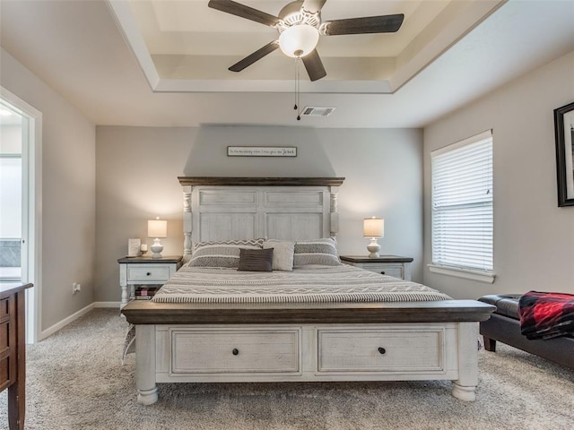 carpeted bedroom with a raised ceiling, a ceiling fan, and baseboards