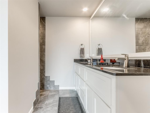 bathroom with double vanity and baseboards