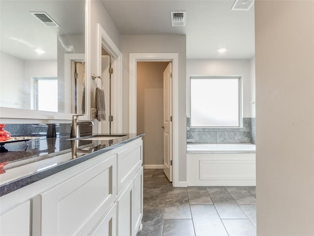 full bath featuring a garden tub, vanity, and baseboards