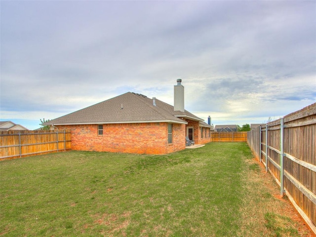 back of house with a chimney, brick siding, and a shingled roof
