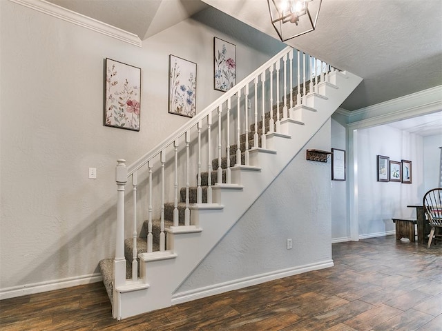 stairway featuring baseboards, a chandelier, crown molding, and wood finished floors