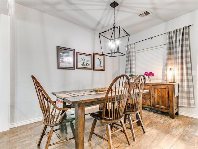 dining area with light wood finished floors, an inviting chandelier, visible vents, and baseboards