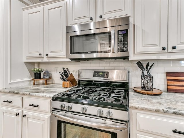 kitchen with backsplash, white cabinets, and appliances with stainless steel finishes