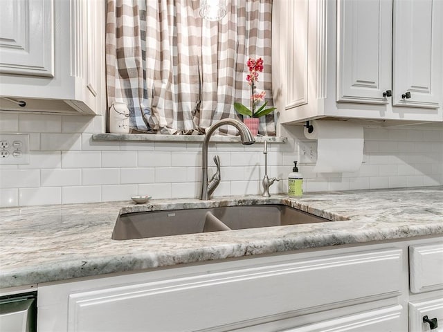 kitchen featuring backsplash, white cabinets, and a sink