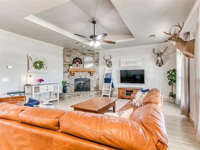 living area with a ceiling fan, crown molding, visible vents, a raised ceiling, and light wood-style floors