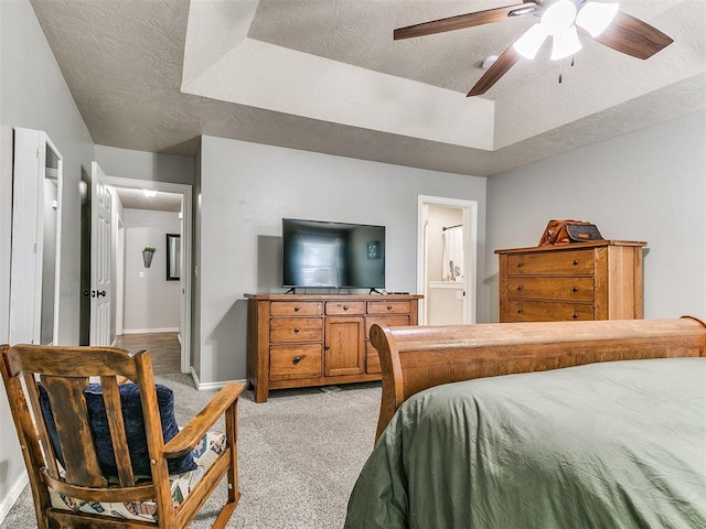 bedroom with light colored carpet, a textured ceiling, baseboards, and a raised ceiling