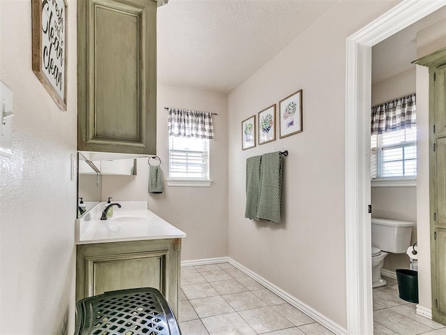 bathroom featuring tile patterned floors, toilet, vanity, and a healthy amount of sunlight