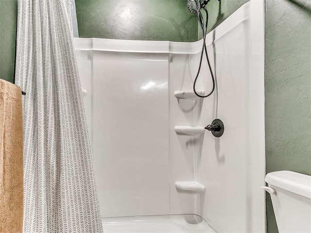 full bathroom with toilet, a shower with shower curtain, and a textured wall