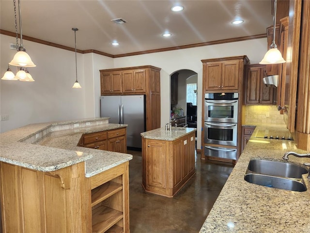 kitchen featuring a spacious island, a sink, stainless steel appliances, arched walkways, and concrete floors