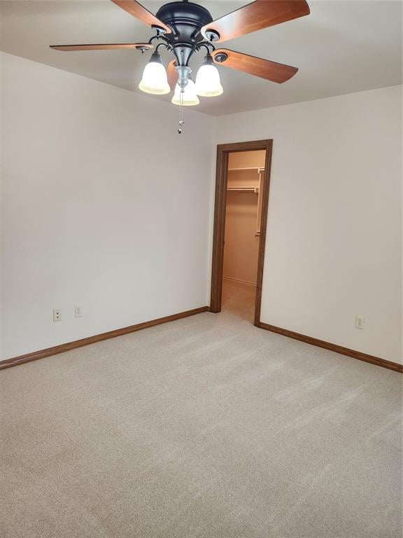 empty room with ceiling fan, light carpet, and baseboards