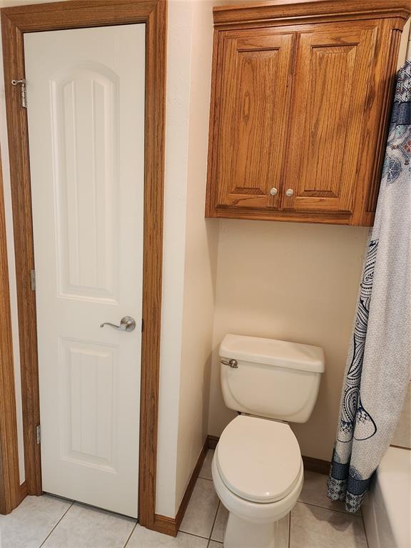 full bath with baseboards, toilet, and tile patterned flooring