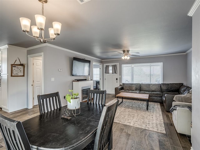2013 N Draper Ave, Choctaw, OK 73020 - dining area featuring a glass covered fireplace, ornamental molding, ceiling fan with notable chandelier, and dark wood-type flooring