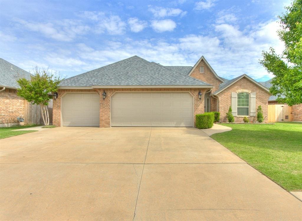 ranch-style house featuring brick siding, driveway, a front yard, and an attached garage