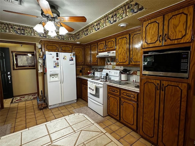 16296 N County Road 3264th Rd, Pauls Valley, OK 73075 - kitchen featuring white appliances, tile counters, under cabinet range hood, a ceiling fan, and light tile patterned floors