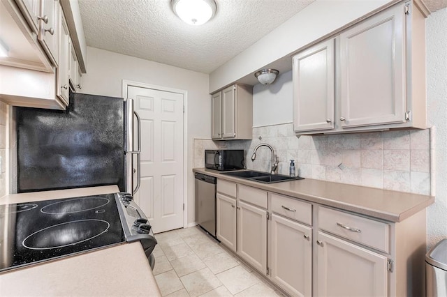 kitchen featuring a textured ceiling, tasteful backsplash, a sink, light countertops, and black appliances