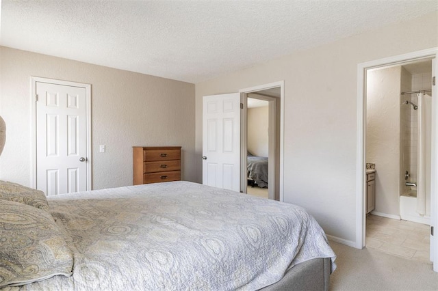 bedroom with connected bathroom, a textured ceiling, and light colored carpet