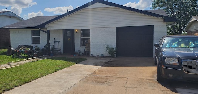 view of front of house featuring a front yard, a garage, brick siding, and driveway