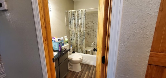 full bath with toilet, vanity, shower / bathtub combination with curtain, wood finished floors, and a textured wall