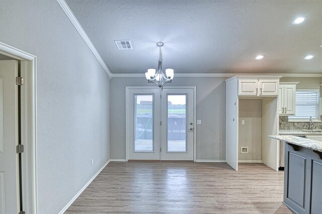 34701 E County Road 1610, Pauls Valley, OK 73075 - unfurnished dining area with light wood finished floors, a sink, a notable chandelier, crown molding, and visible vents