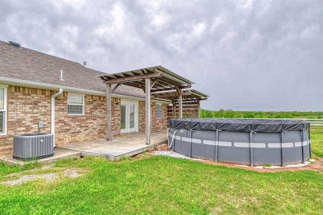 34701 E County Road 1610, Pauls Valley, OK 73075 - back of property featuring a pergola, a covered pool, a deck, a lawn, and central air condition unit