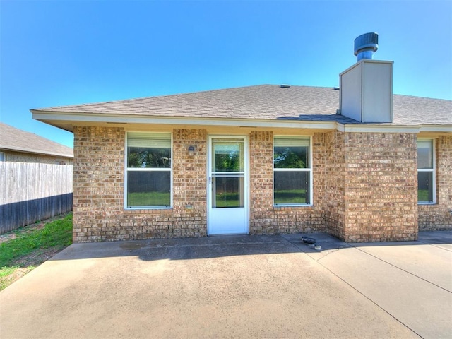8233 Greer Way, Oklahoma City, OK 73132 - rear view of house with fence, brick siding, a patio area, and roof with shingles