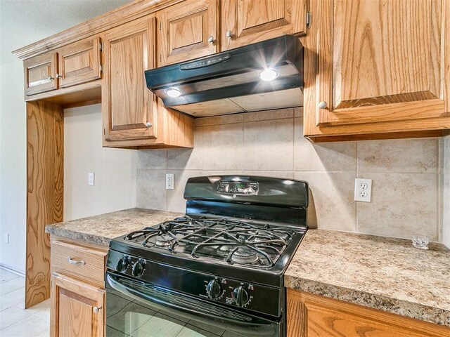 8233 Greer Way, Oklahoma City, OK 73132 - kitchen featuring black range with gas stovetop, under cabinet range hood, decorative backsplash, light countertops, and light tile patterned flooring