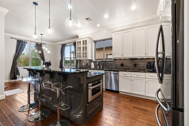 kitchen with a breakfast bar area, crown molding, visible vents, appliances with stainless steel finishes, and tasteful backsplash