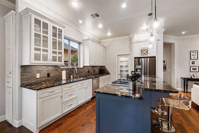 kitchen featuring a sink, stainless steel appliances, a breakfast bar, visible vents, and decorative backsplash