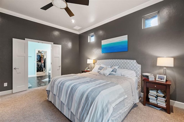 carpeted bedroom featuring multiple windows, ornamental molding, ceiling fan, a spacious closet, and baseboards