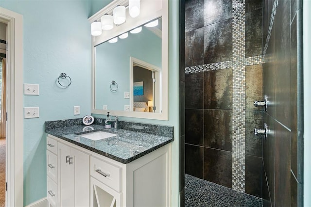 full bathroom featuring a tile shower and vanity