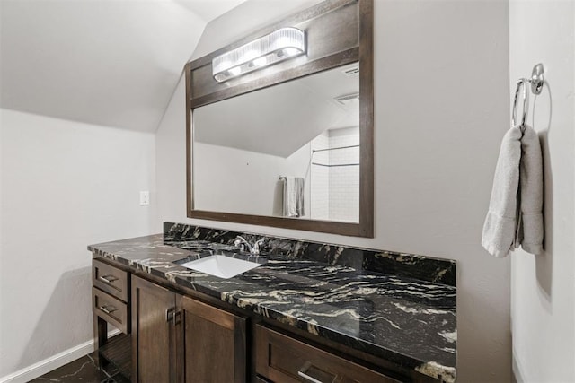 bathroom with vanity, lofted ceiling, and baseboards