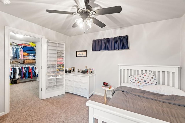 bedroom with a ceiling fan, a closet, baseboards, a spacious closet, and light carpet