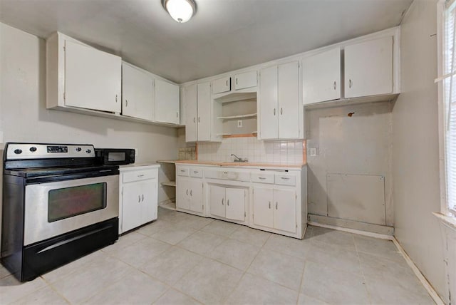 3924 Teal Dr, Del City, OK 73115 - kitchen featuring stainless steel range with electric stovetop, black microwave, light tile patterned floors, and white cabinets