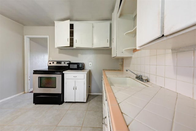 3924 Teal Dr, Del City, OK 73115 - kitchen featuring stainless steel electric range oven, tile countertops, a sink, black microwave, and white cabinets