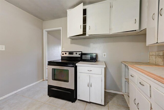 3924 Teal Dr, Del City, OK 73115 - kitchen with electric range, tile counters, and white cabinetry