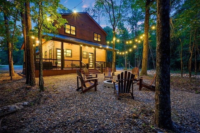 back of house with a fire pit, covered porch, and metal roof