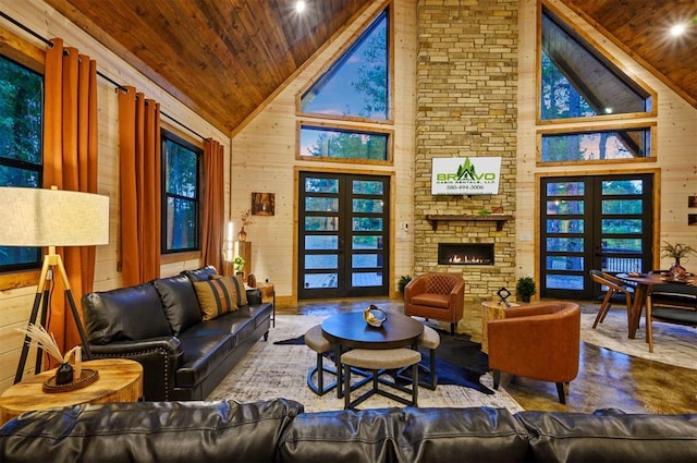 living room featuring wooden ceiling, high vaulted ceiling, wood walls, a stone fireplace, and french doors