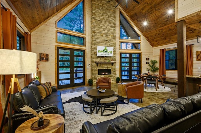 living room with wood ceiling, high vaulted ceiling, a stone fireplace, wood walls, and french doors