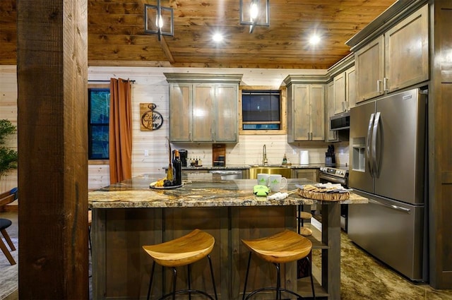 kitchen with stainless steel appliances, a sink, wood ceiling, a kitchen breakfast bar, and wooden walls