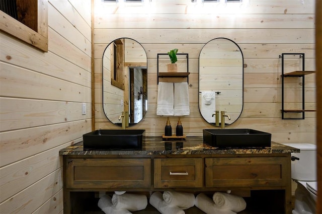 bathroom featuring wood walls, toilet, and vanity