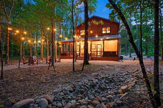 back of property with an outdoor fire pit, a porch, and metal roof
