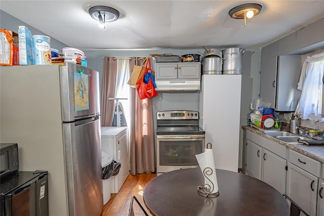 2717 SW 42nd St, Oklahoma City, OK 73119 - kitchen with a sink, under cabinet range hood, light wood finished floors, washing machine and clothes dryer, and appliances with stainless steel finishes