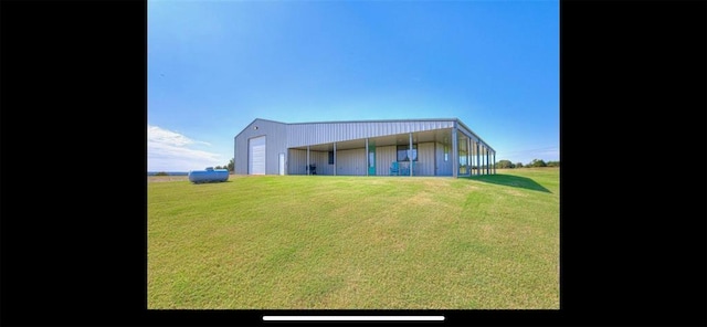 back of property featuring a yard, a detached garage, and an outdoor structure