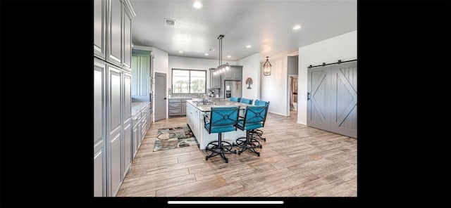 kitchen featuring a barn door, stainless steel fridge with ice dispenser, a kitchen breakfast bar, a kitchen island, and light countertops